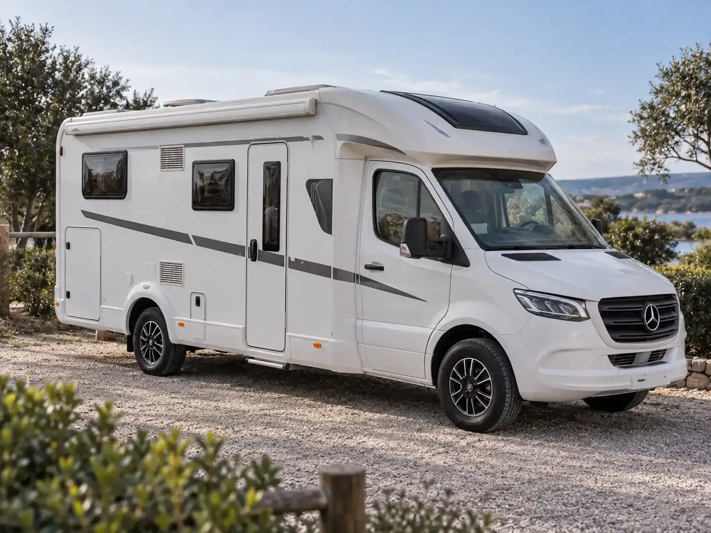 Wohnmobil mit geschlossener Aufbautür auf einem Stellplatz am Wasser